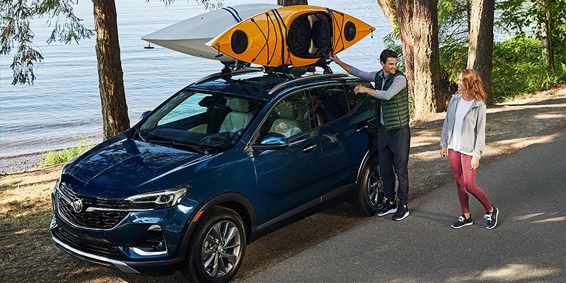 couple putting kayak on blue Buick Encore GX