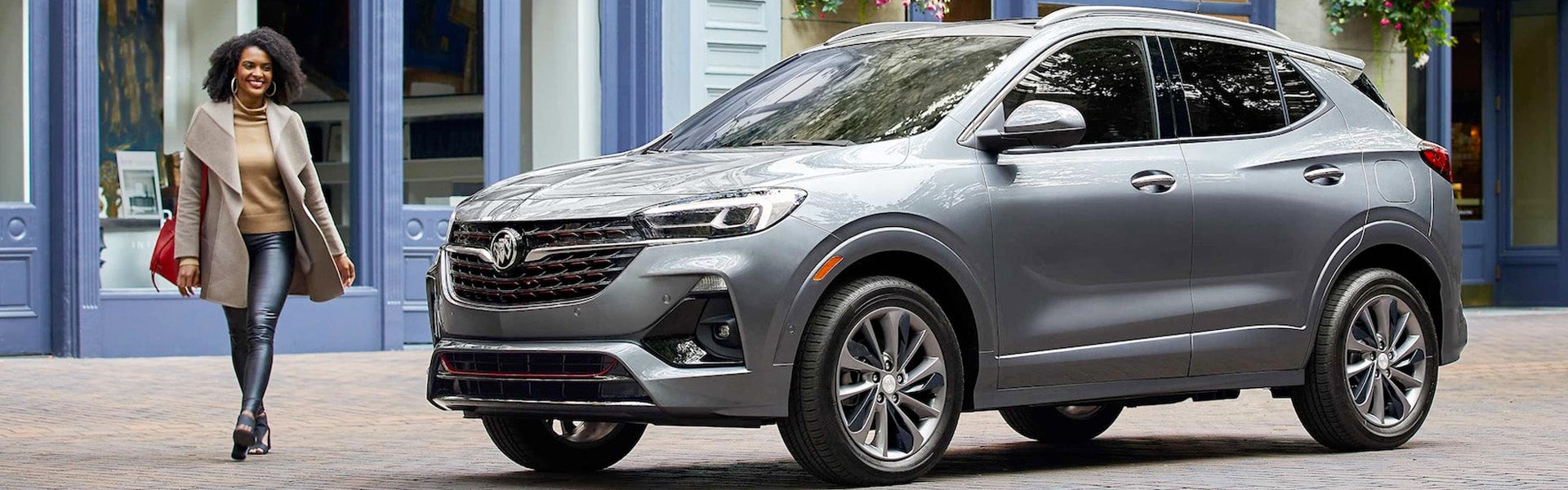 girl passing by silver Buick Encore GX